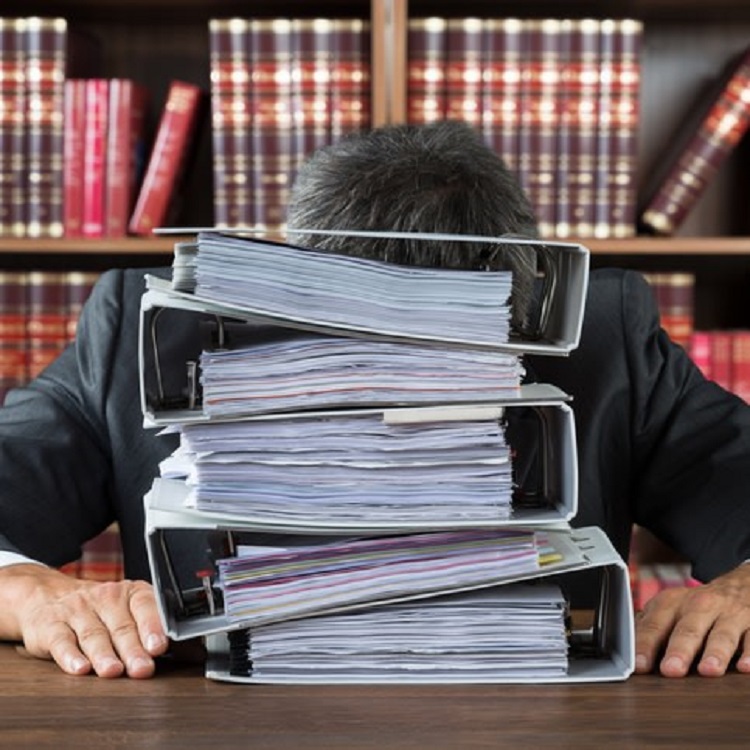 Image of a man asleep on books at a desk